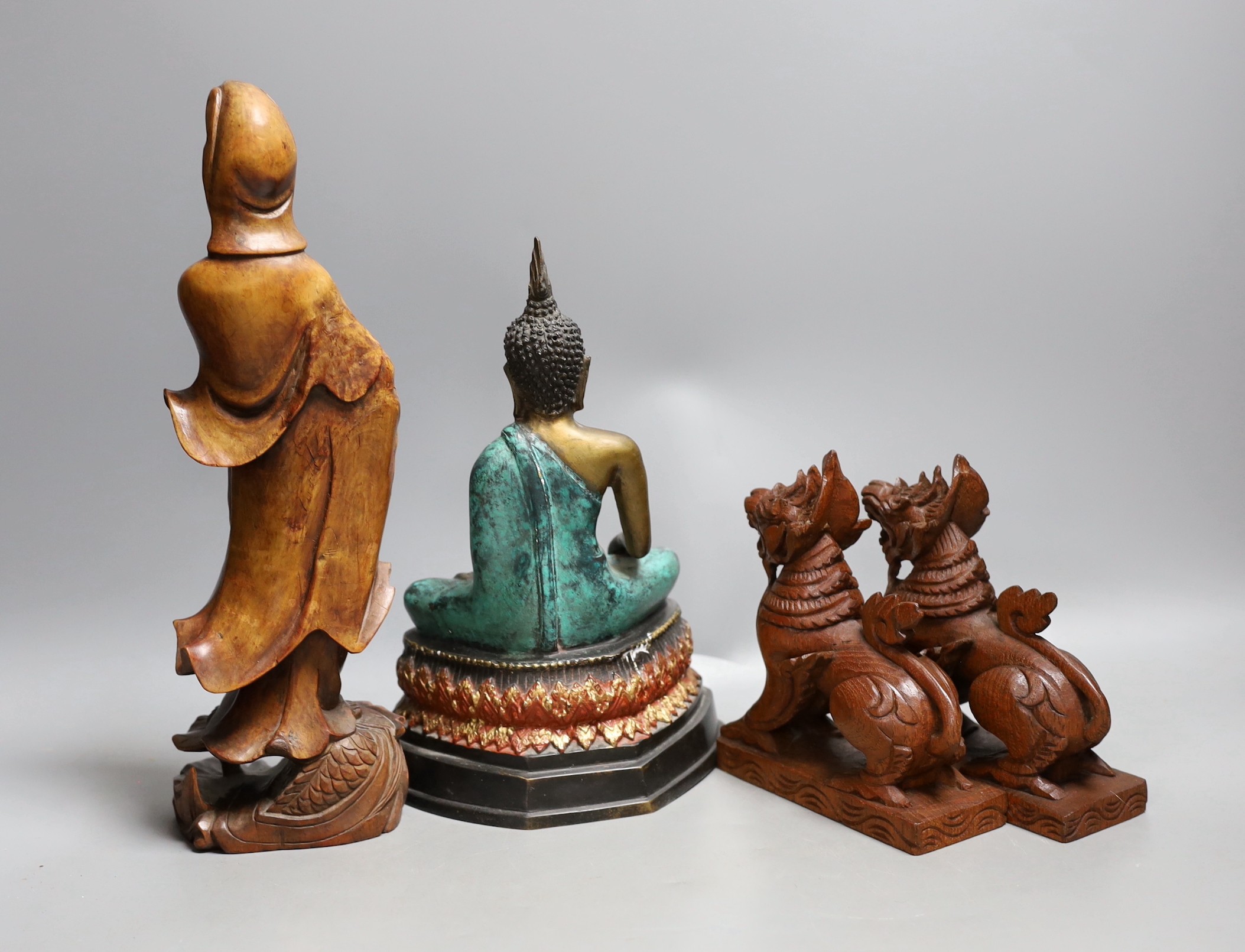 A Chinese carved wood figure of Guanyin, a pair of Buddhist lions and a cast brass figure of Buddha, tallest 30cm